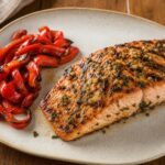 Beer marinated grilled salmon fillet with garlic, ginger, cilantro, and roasted red peppers on a serving platter