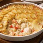 Creamy halibut and shrimp fish pie with a thin overlapping sliced potato top in a baking dish