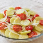 Cucumber tomato and onion salad with peeled cucumber slices, halved cherry tomatoes, and sweet onion in vinaigrette