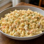 Creamy cavatappi with visible Dungeness crab, toasted panko, grated cheese, and chopped parsley in a ceramic bowl