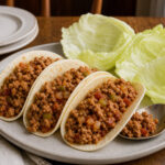 Ground turkey tacos in soft tortillas with iceberg lettuce leaves beside them