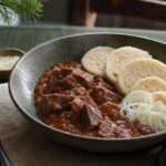 Prague beef goulash with tender beef cubes, red-brown paprika sauce, bread dumplings, and sliced onion