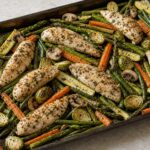 Garlic chicken tenders roasted with asparagus, carrots, zucchini, Brussels sprouts, green beans, and mushrooms on a sheet pan