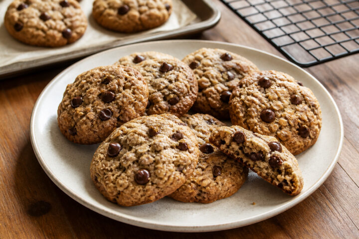 Round sugar-crusted oatmeal chocolate chip cookies with golden edges and one broken cookie showing the tender oat crumb